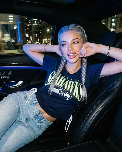 Adult woman with long braids in a car at night with city lights outside