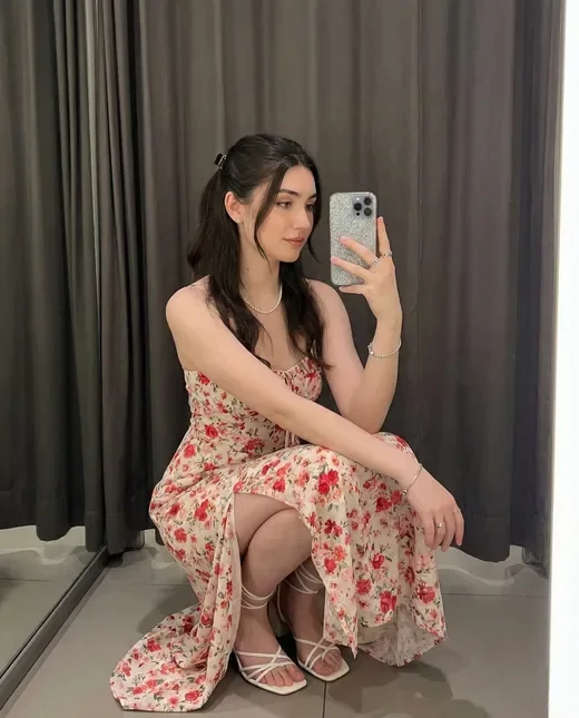 Adult virtual companion in a floral summer dress taking a mirror selfie